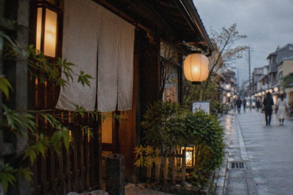 A traditional Kyoto restaurant entrance with warm lanterns glowing at dusk