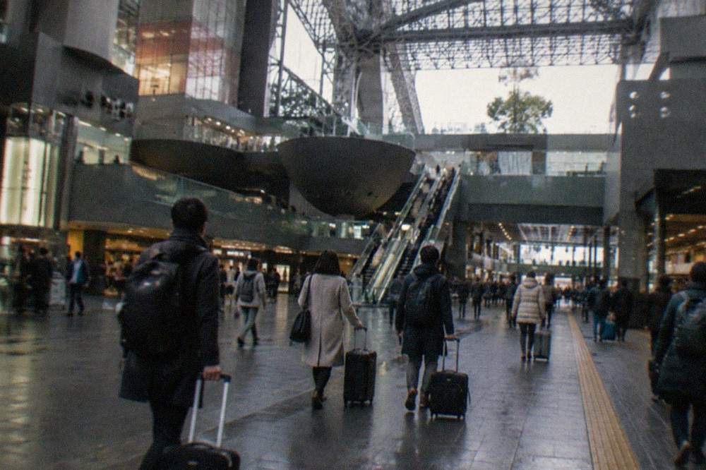 Travellers with suitcases walking through the large atrium of Kyoto Station