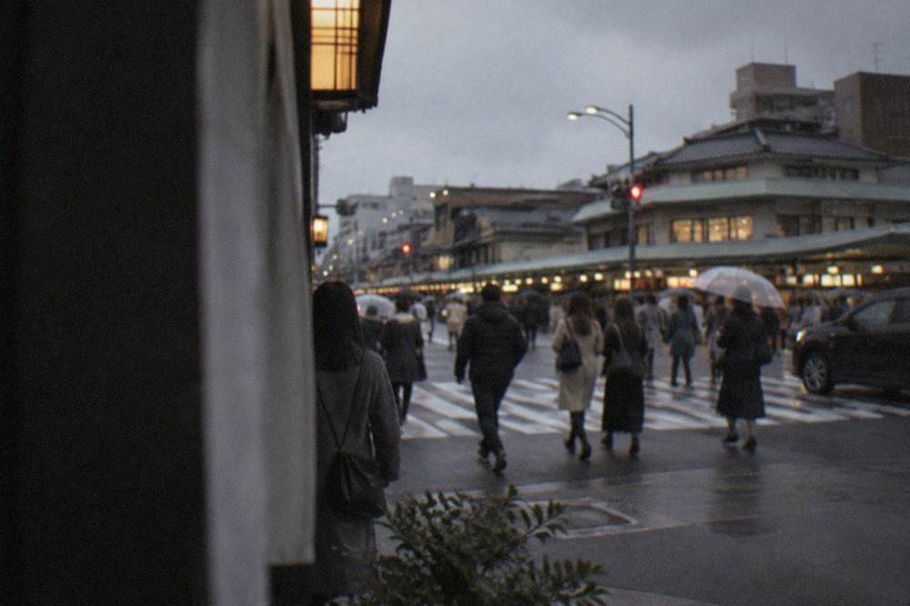 Evening crowds crossing a lit intersection on Shijo-dori in downtown Kyoto