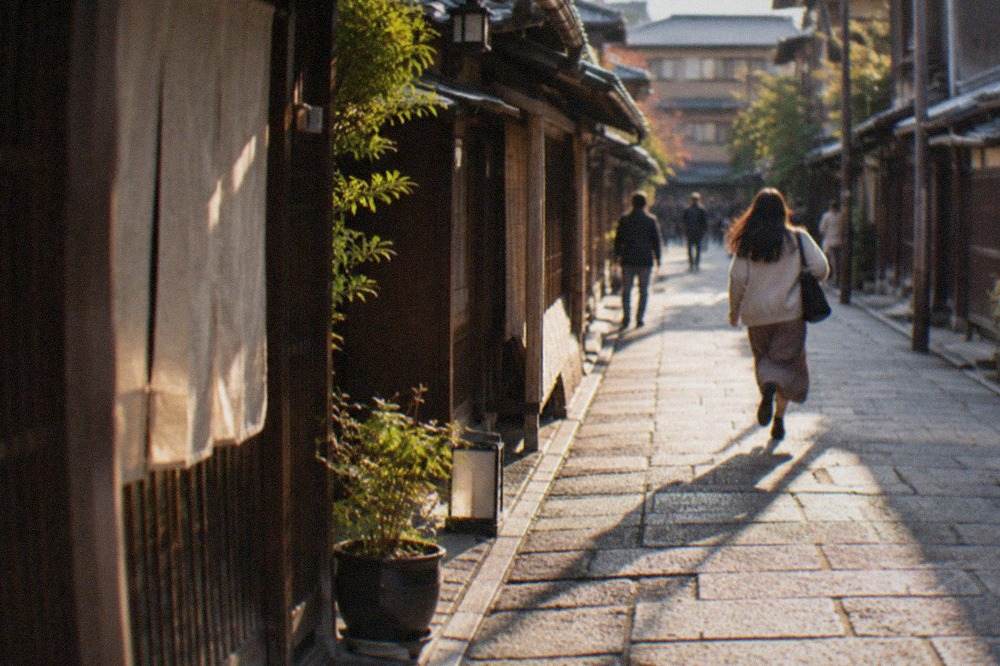 Traditional wooden machiya houses lining a quiet stone street in Kyoto at golden hour
