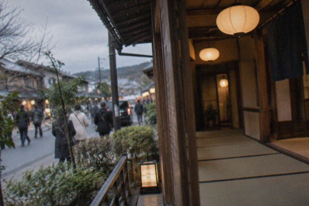 A traditional wooden ryokan corridor with tatami flooring and paper lanterns glowing in the evening
