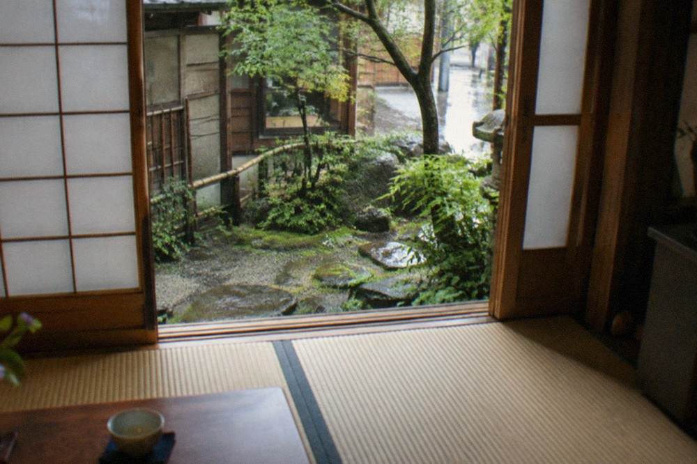Interior of a traditional Kyoto house with tatami mats, paper shoji screens and a view to a small courtyard garden