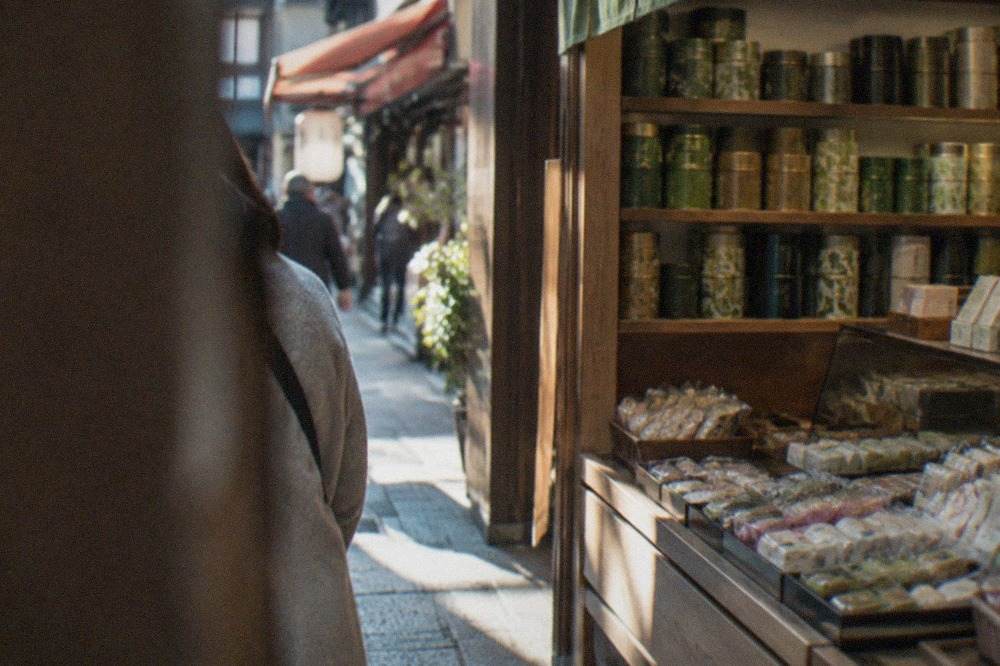 Shop shelves stacked with tins of green tea and packaged sweets in a Kyoto storefront