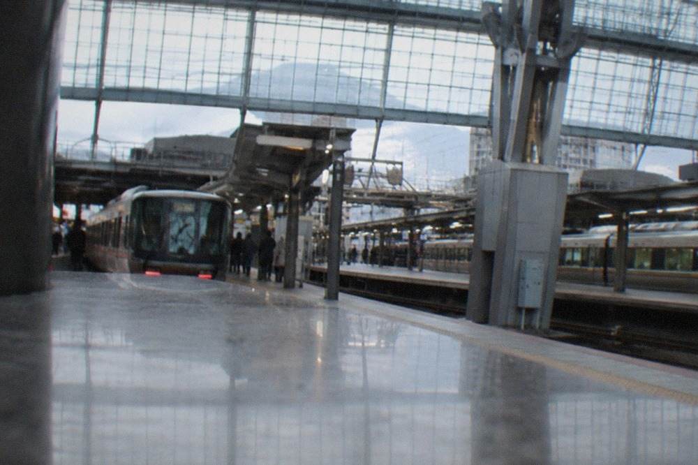 Trains lined up on the platforms of Kyoto Station under the station's tall glass concourse