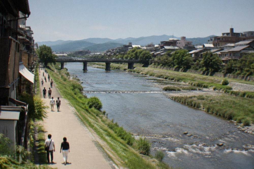 An underground railway platform beside the Kamo River with a train arriving