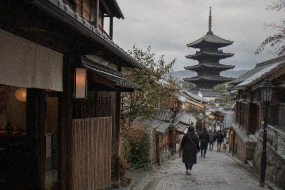 Stone-paved Sannenzaka lane lined with traditional wooden machiya shopfronts below the temple