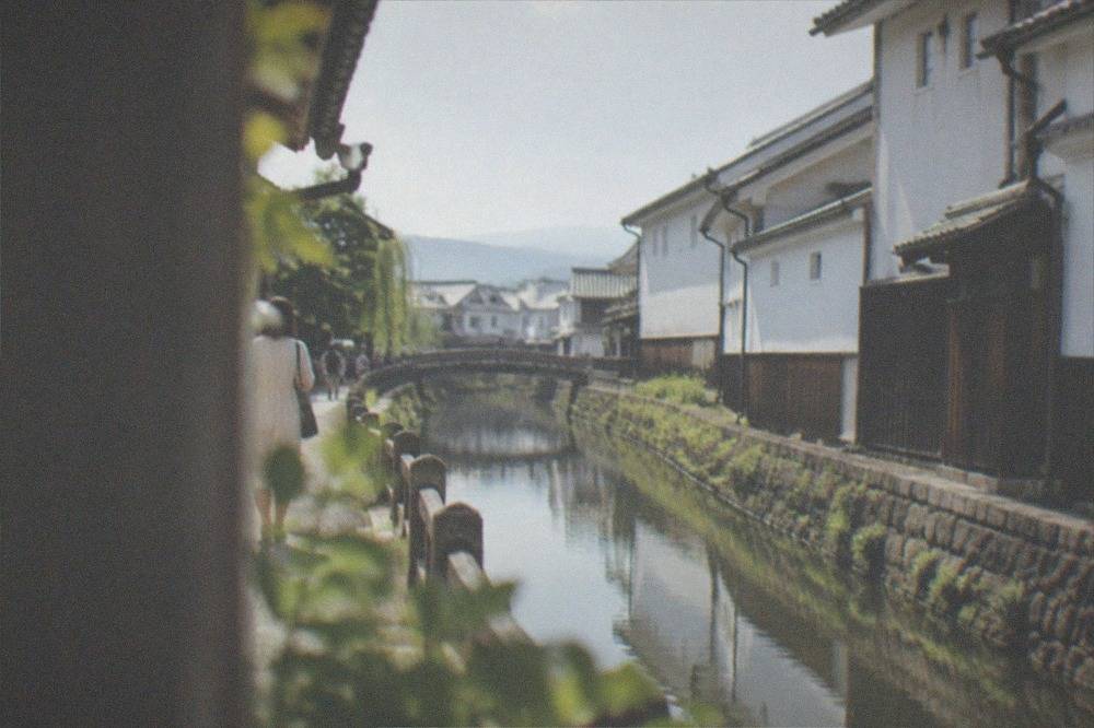 White-walled sake brewery buildings along a quiet canal in the Fushimi district