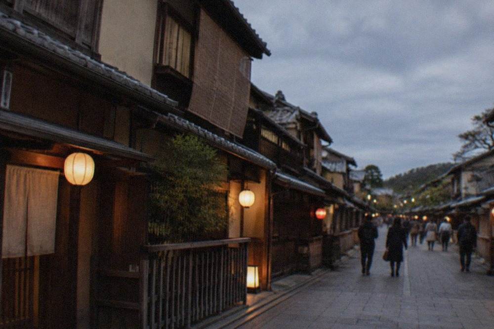 A traditional wooden machiya street in Gion at dusk with lanterns lit