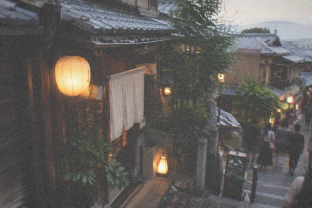 Lantern-lit wooden facade of a traditional teahouse district street in the evening