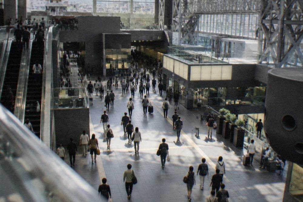 Commuters walking through the broad station concourse beneath the tall atrium of Kyoto Station