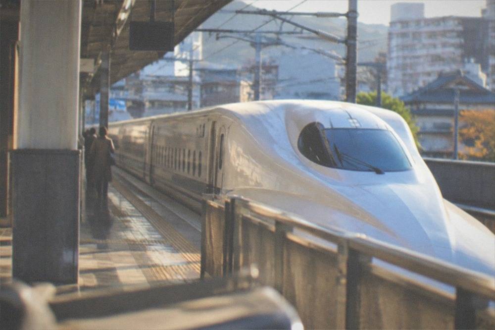 A white Shinkansen bullet train stopped at a platform inside a station in Japan