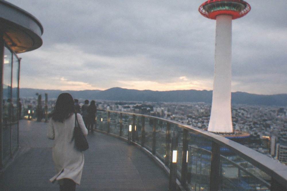 The observation deck of Kyoto Tower at dusk with the city spreading out to the mountains beyond