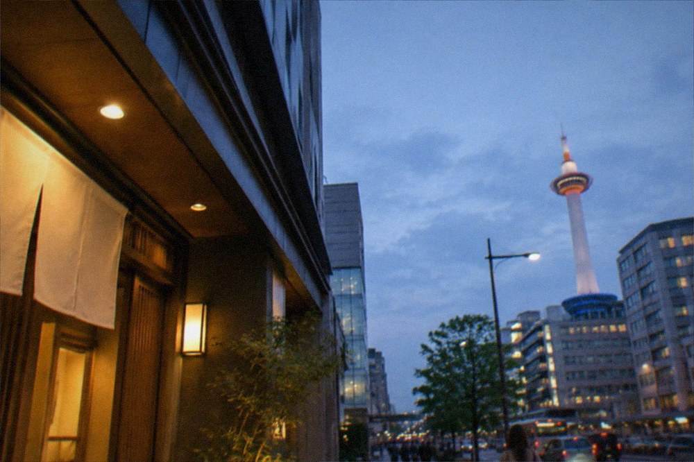 A clean modern hotel room with a city view window and a bed with white linens