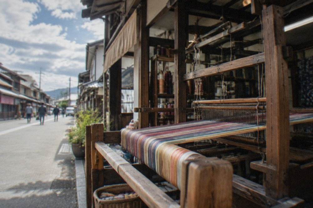 A wooden handloom with colorful silk threads stretched across it in a workshop