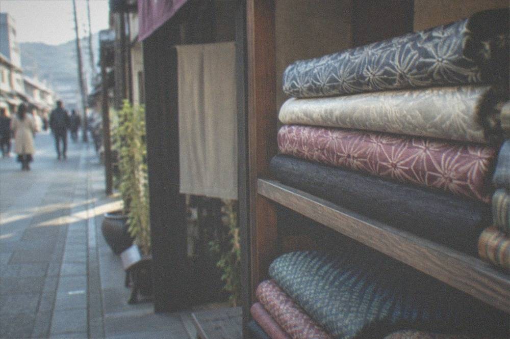 Folded silk fabrics with woven geometric patterns stacked on a shop shelf