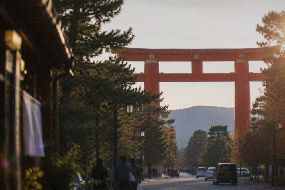 The large red torii gate of Heian Shrine towering over the tree-lined approach in Kyoto's Okazaki district