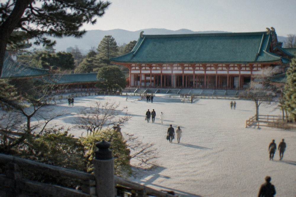 The green and white shrine hall of Heian Shrine seen across its wide white gravel forecourt