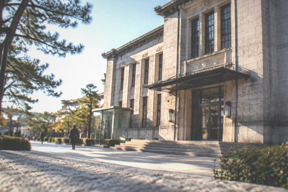 The stone facade of a large art museum building in Kyoto's Okazaki park on a clear day