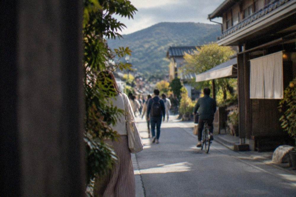 A single-car tram crossing a street in the Arashiyama district