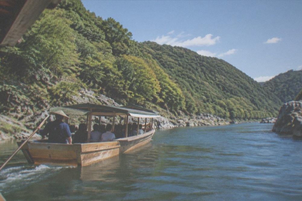 A wooden river boat carrying passengers along the Hozugawa gorge near Arashiyama