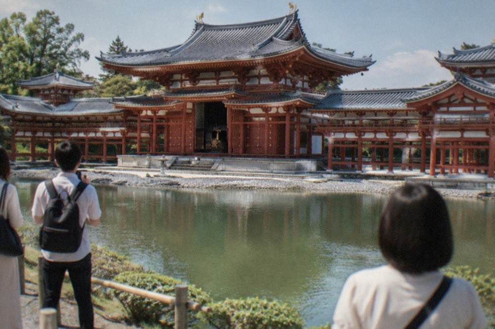 Visitors viewing the Phoenix Hall across the pond from the garden bank at Byodo-in