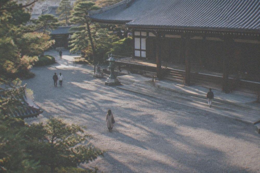 A wide gravel courtyard in front of a large wooden temple hall with a tiled roof