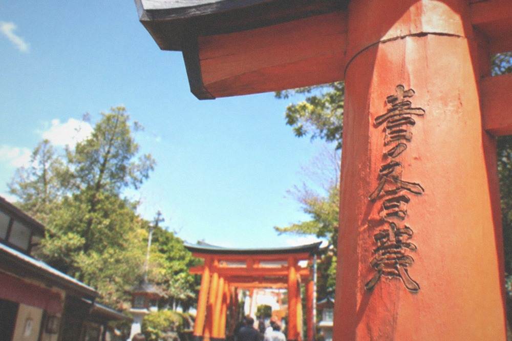 Close view of a torii gate showing carved donor characters