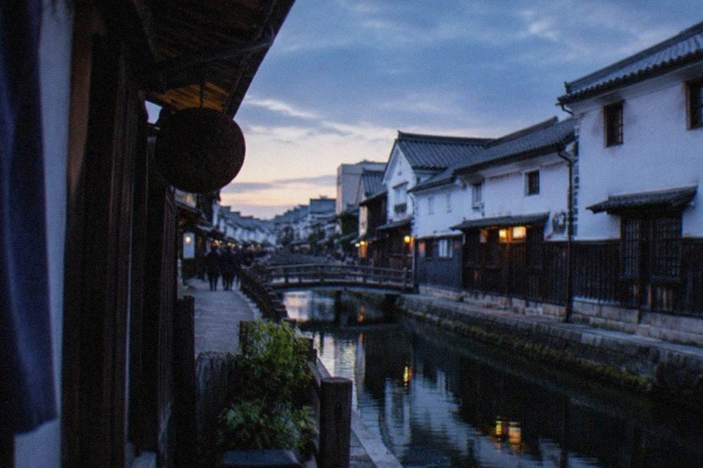 A quiet canal street in the Fushimi sake district lined with traditional white-walled brewery buildings