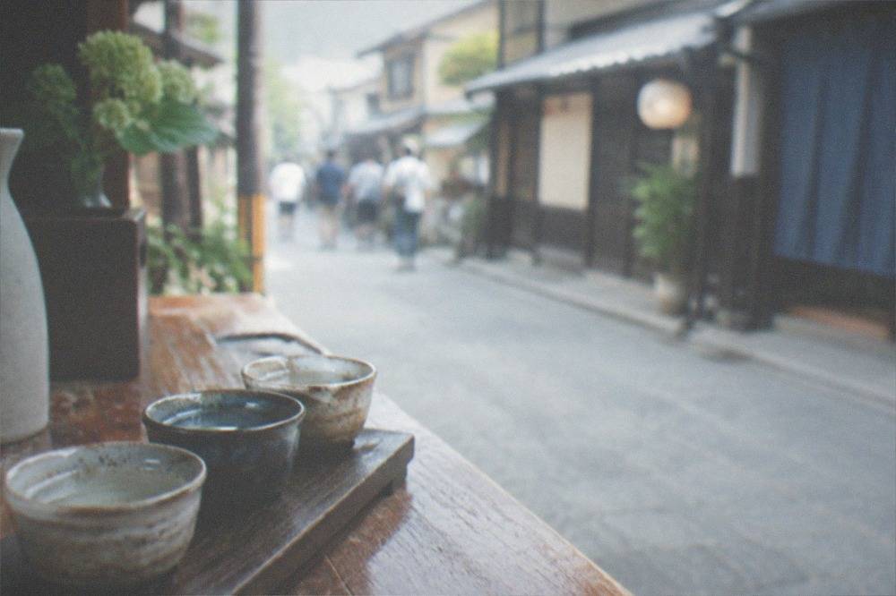 Three small sake tasting cups arranged on a wooden counter