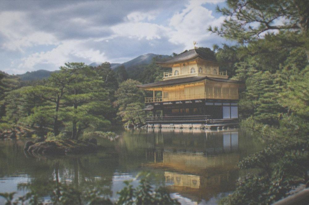 A gold-leafed pavilion across a reflecting pond with pines