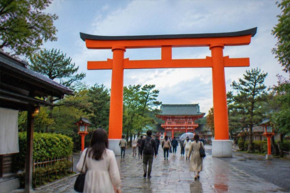 Visitors walking through the torii gate approach toward Heian Shrine