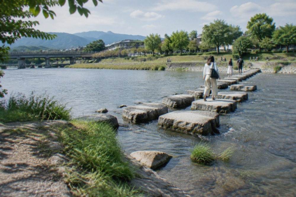 Stepping stones crossing a shallow river at a tree-lined delta in Kyoto