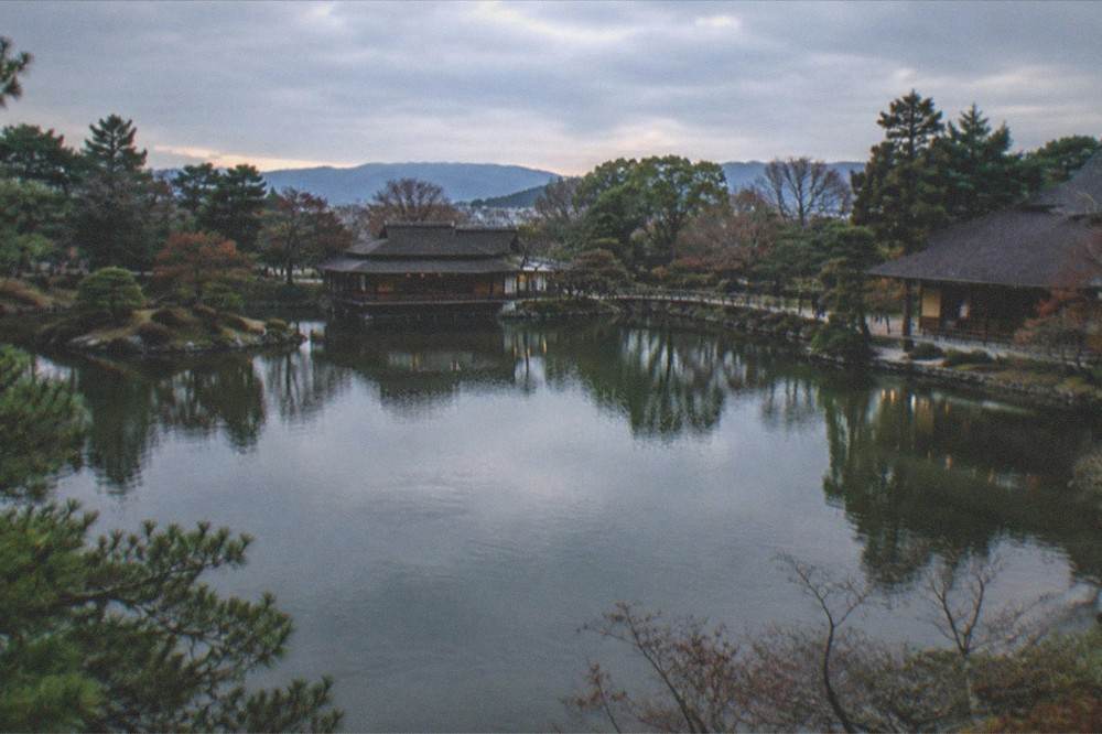 A quiet garden pond at dusk with teahouse silhouettes in Kyoto