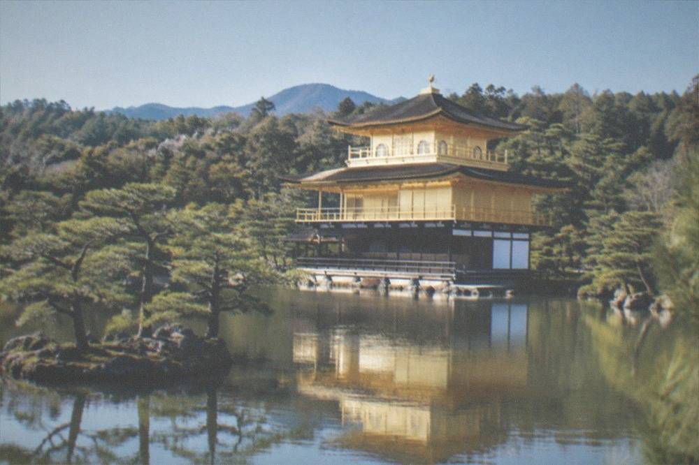 The Golden Pavilion seen from across its pond with clear sky reflected in the water