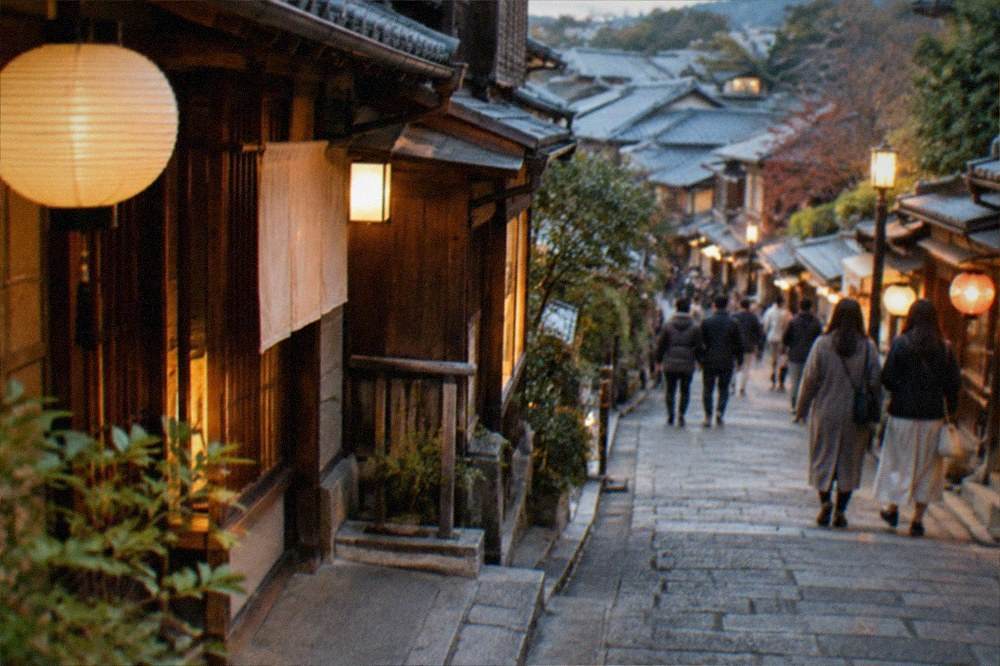A narrow lane in Higashiyama with traditional wooden buildings, paper lanterns and stone paving at dusk