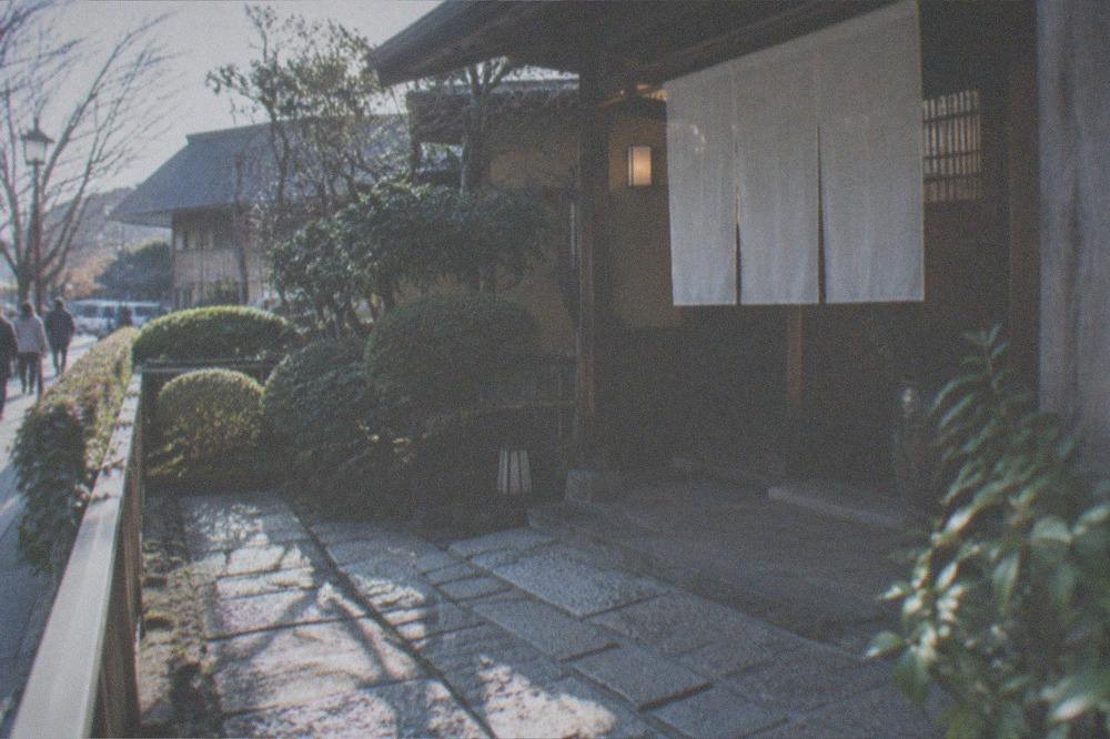 A traditional wooden restaurant entrance with a stone path and neatly trimmed garden