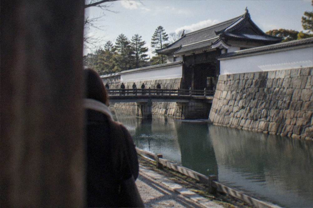 A stone fortification wall and moat with a traditional gate roof at Nijo-jo Castle in Kyoto