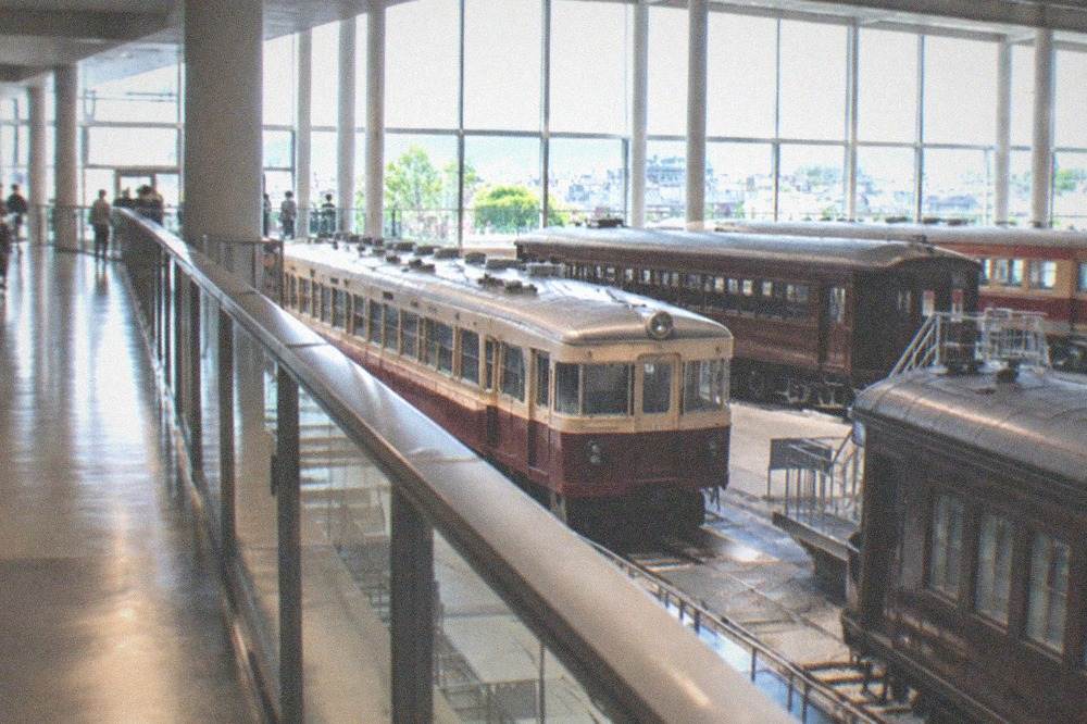 A bright gallery walkway overlooking rows of historic train carriages below