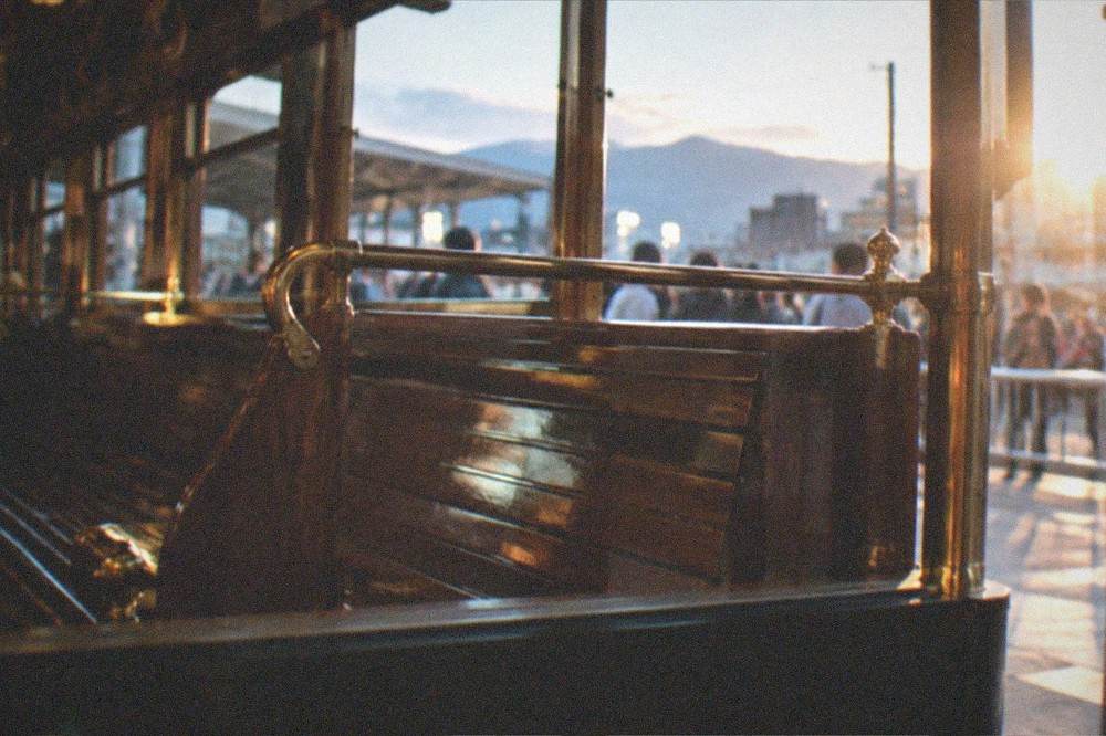 A historic train carriage interior with polished wooden seats and brass fittings preserved behind a viewing barrier