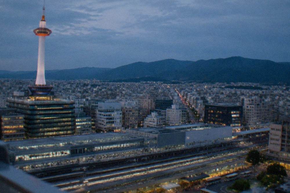 View from the Kyoto Tower observation deck across Kyoto Station and the city grid toward the northern hills
