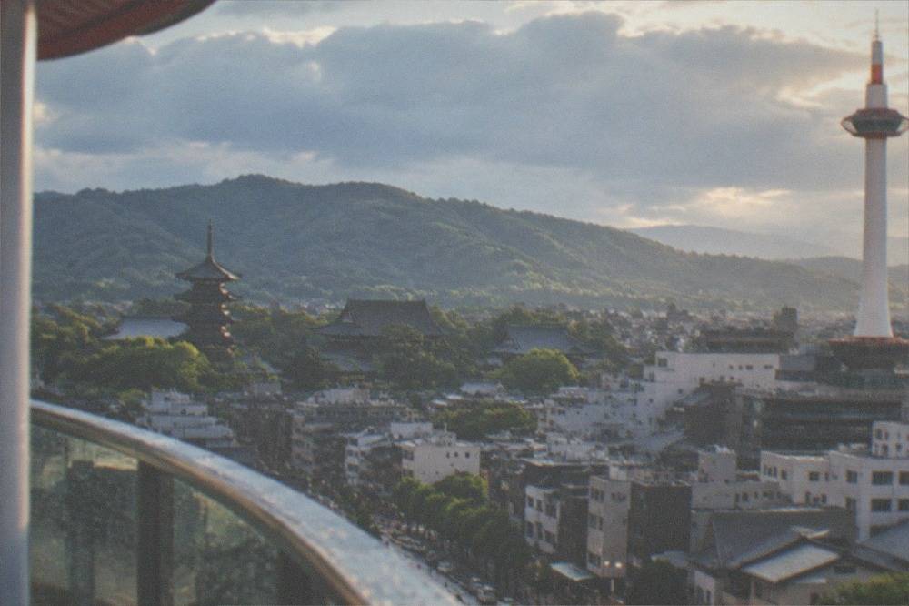 Kyoto's temple rooftops and eastern hills seen from the tower's observation deck in late afternoon light