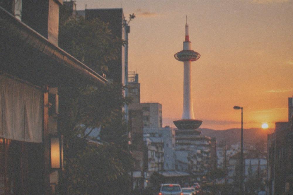 Sunset light falling on Kyoto Tower's white shaft against an orange sky