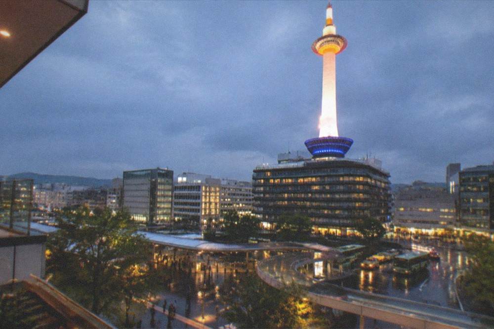 Kyoto Tower illuminated at night above the station plaza