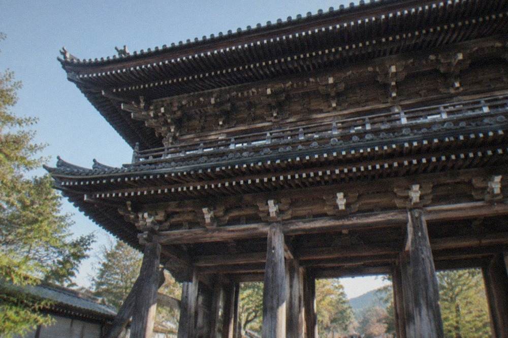 The two-storey Sanmon gate of Nanzen-ji temple seen from below, with wooden beams and tiled roof against a clear sky