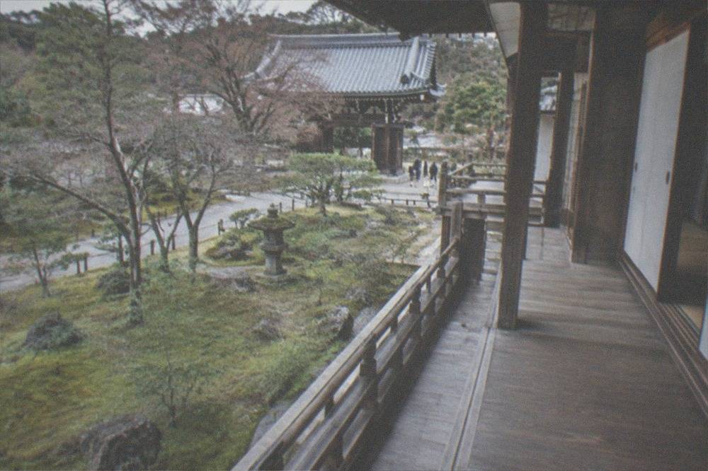 A wooden temple corridor with sliding doors opening onto a garden of moss and stone