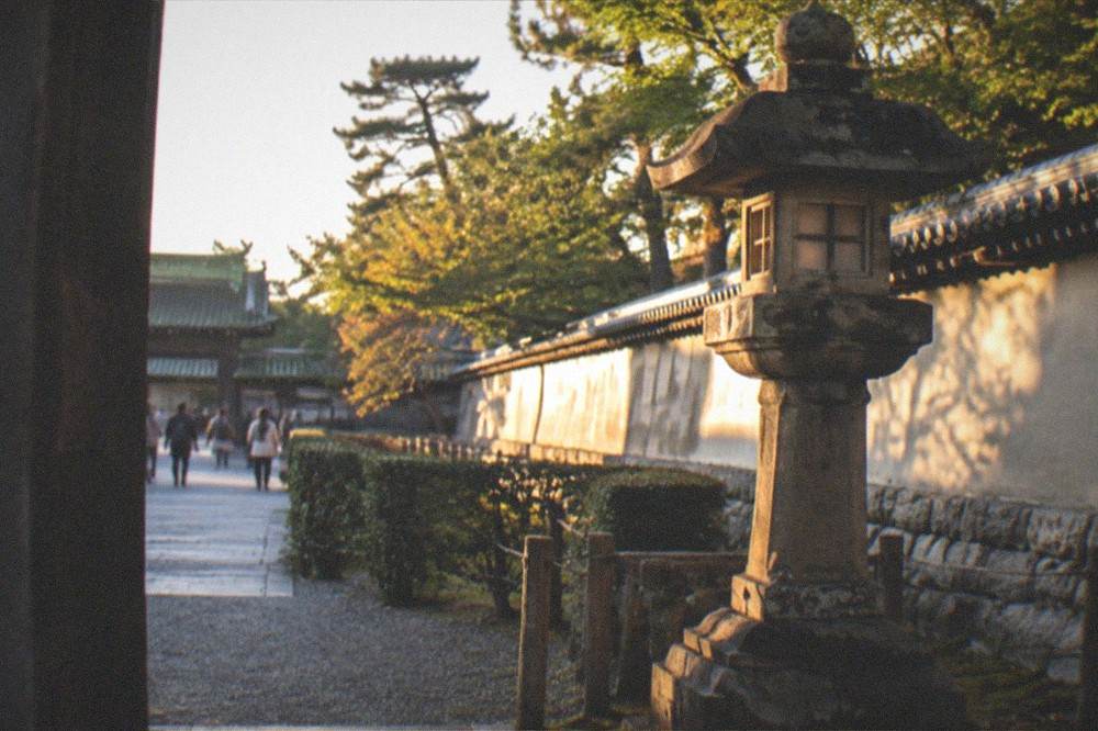A stone lantern and old wall along the castle grounds at Nijo Castle