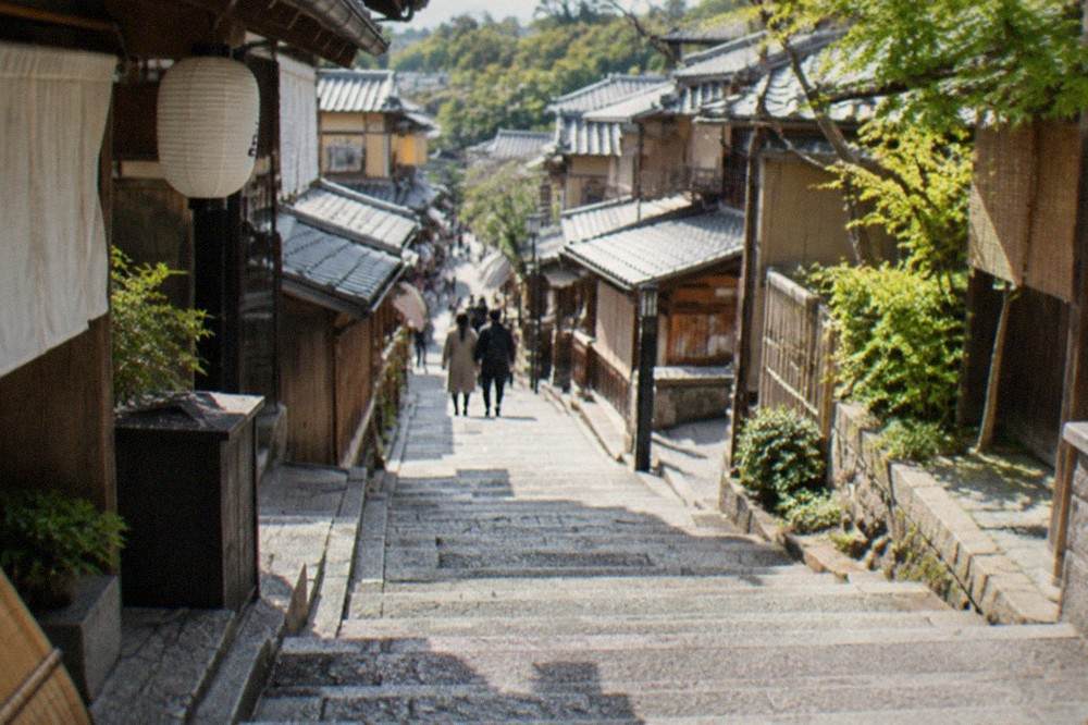 Worn stone steps of Sannenzaka rising between wooden teahouses in Kyoto