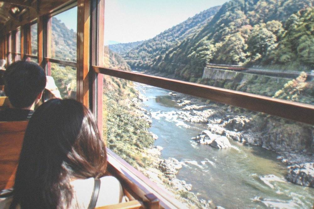 Interior of a vintage carriage with polished wood trim and large windows facing the river gorge