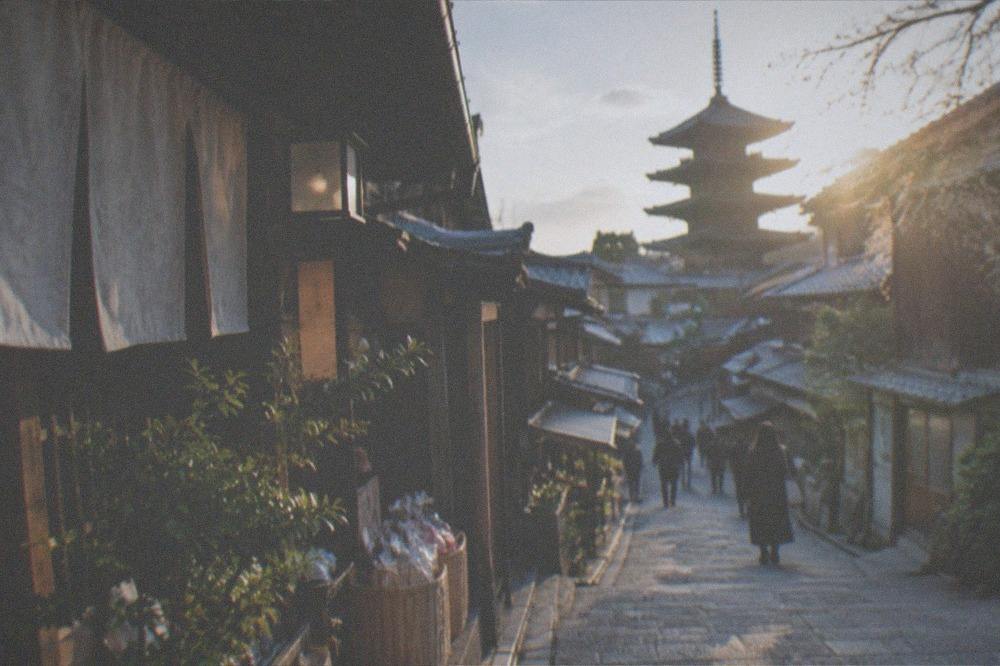 A sloped stone-paved street lined with traditional wooden shopfronts in eastern Kyoto