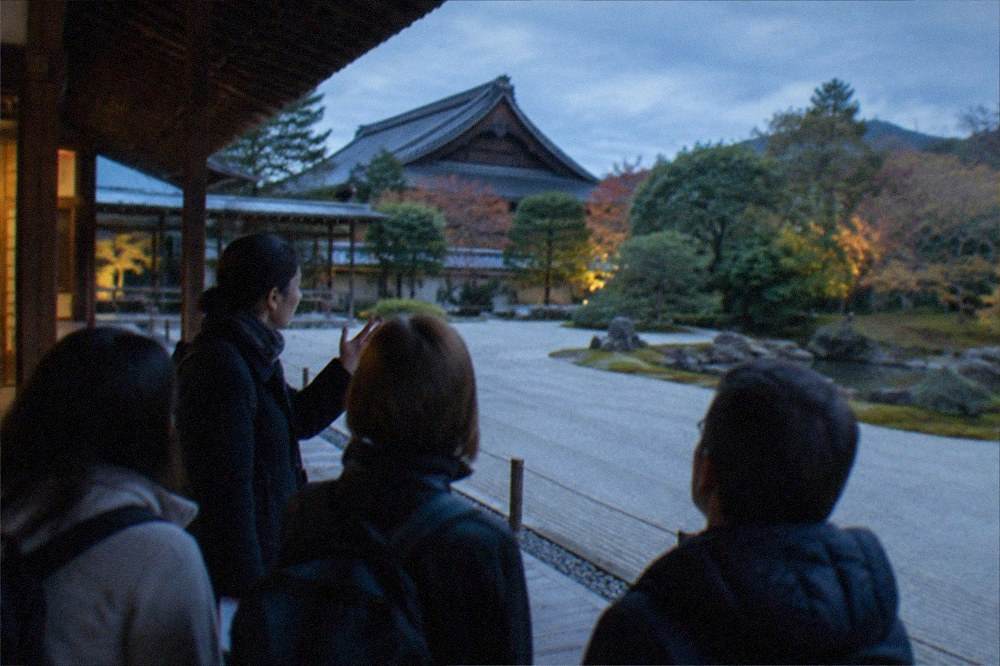 A guide speaking to a small group on a temple veranda